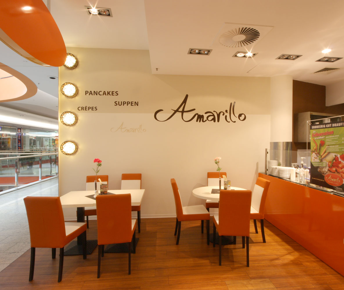 Café mit orange-weißen Stühlen und braun-beiger Wandgestaltung