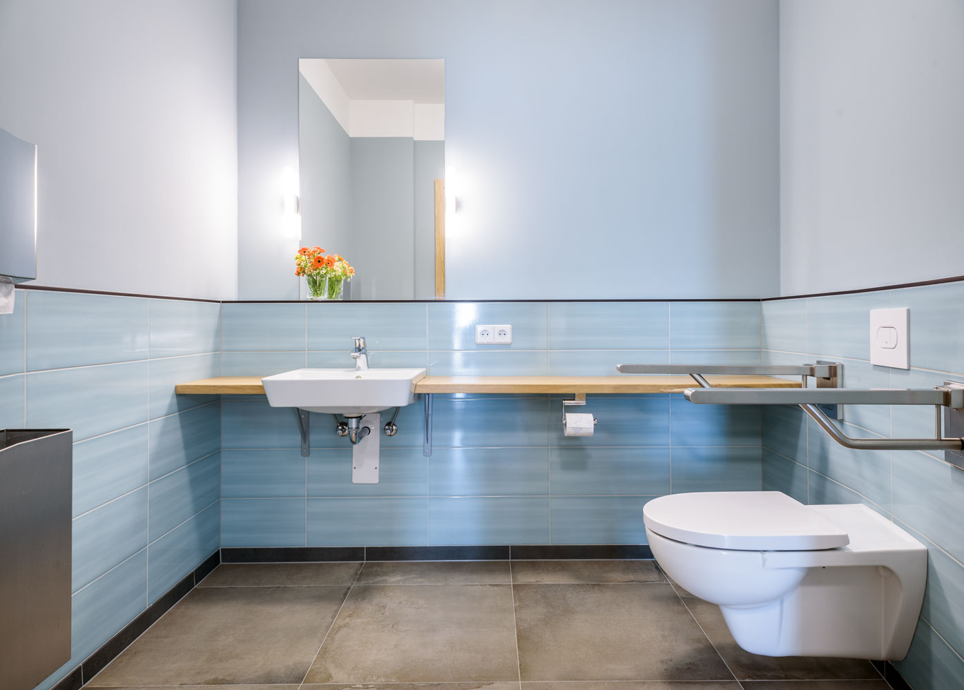 Barrierefreies Kunden-WC mit hellblauen Fliesen