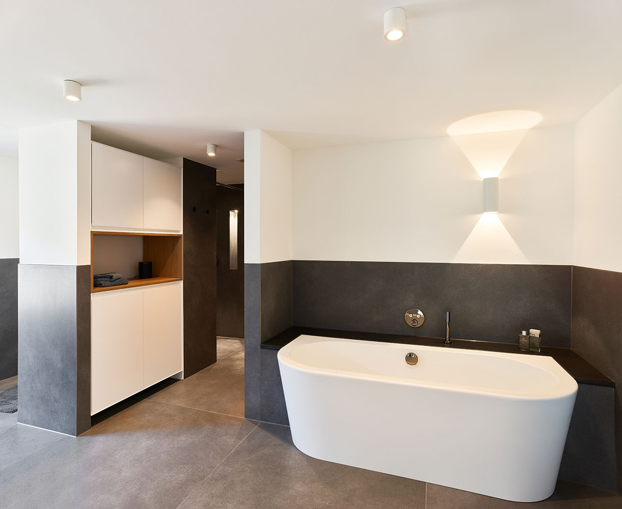modernes Bad mit Halbeinbauwanne und Einbauschrank, Farbkonzept minimalistisch anthrazit und weiß mit warmen Holzakzenten.
