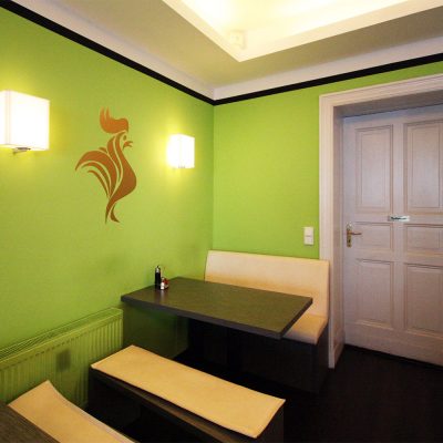 der Hahn als Namensgeber in Gold auf der Wand