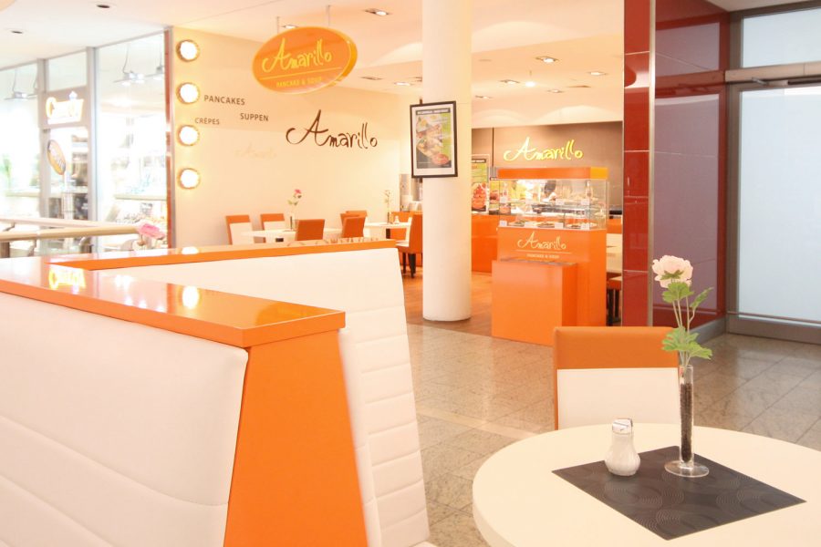 Bistro mit orangen Möbeln in einer Einkaufspassage