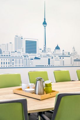 Detail vom Konferenztisch mit grünen Stühlen und Motivtapete