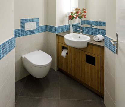 Gäste-WC mit Waschtischschrank aus Bambus und blauem Mosaikstreifen