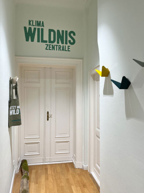 Eingangsbereich mit Schriftzug "KlimaWildnisZentrale" mit weißen Altbau-Türen.